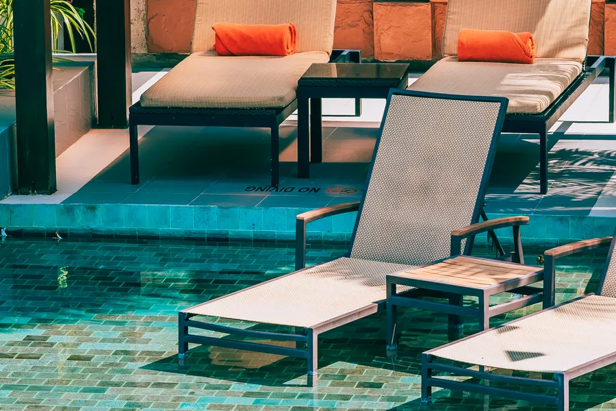 Resort pool deck with loungers against a stone wall